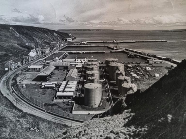 An old picture of Scrabster harbour in black and white taken from the south end looking over the fuel tanks